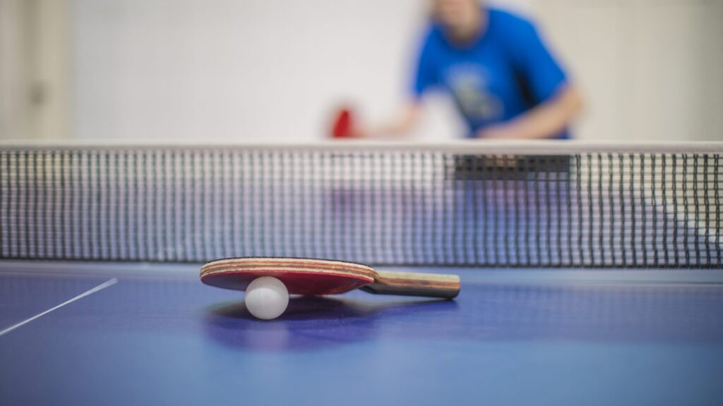 Une raquette de tennis de table est posée par dessus une balle sur la table
