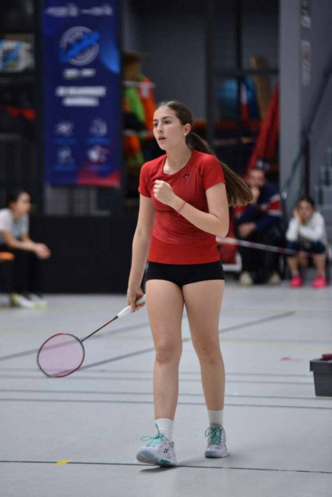 Une jeune fille au couleurs du SCB Badminton sert le point après avoir marqué un point