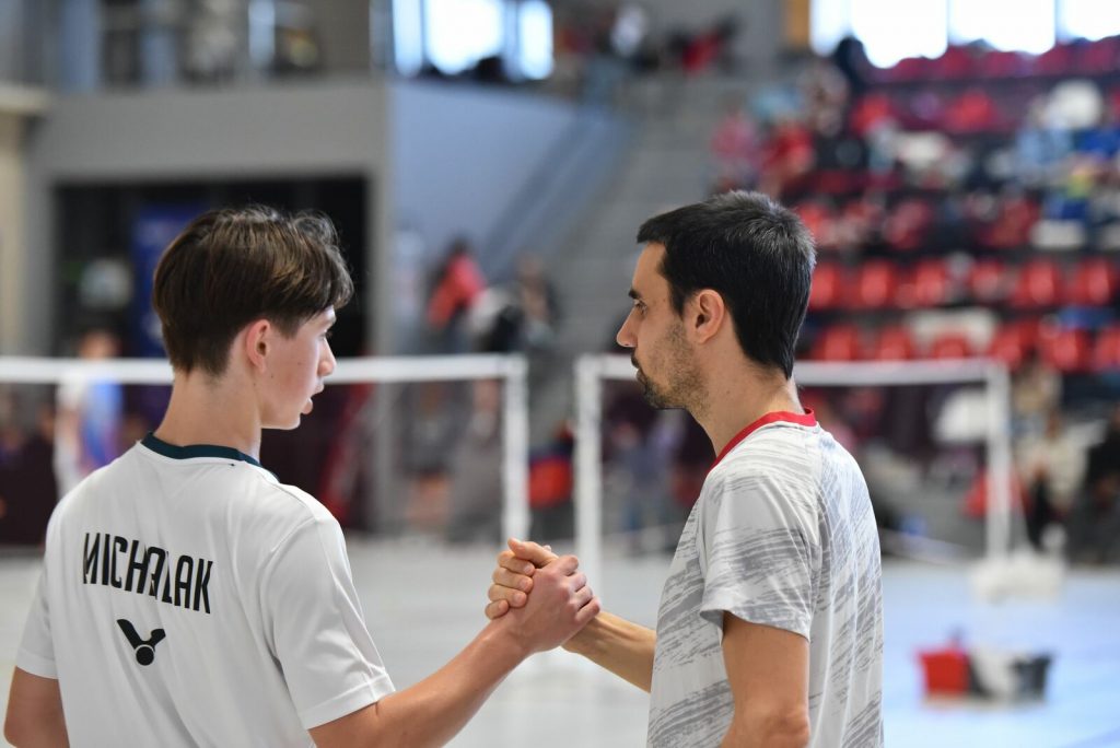 Un coach et son badiste adolescent se serrent les mains.